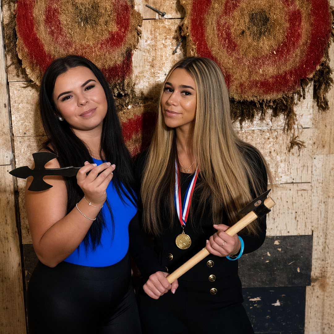 Two players celebrating in front of axe throwing targets